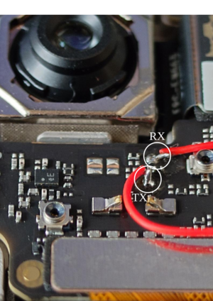 UART pads with wires soldered to them. The top pad is RX and the bottom pad is TX. They are located slightly to the right and below the camera on the motherboard.
